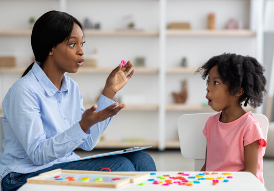 pediatric speech therapist working with child on mouthing letters