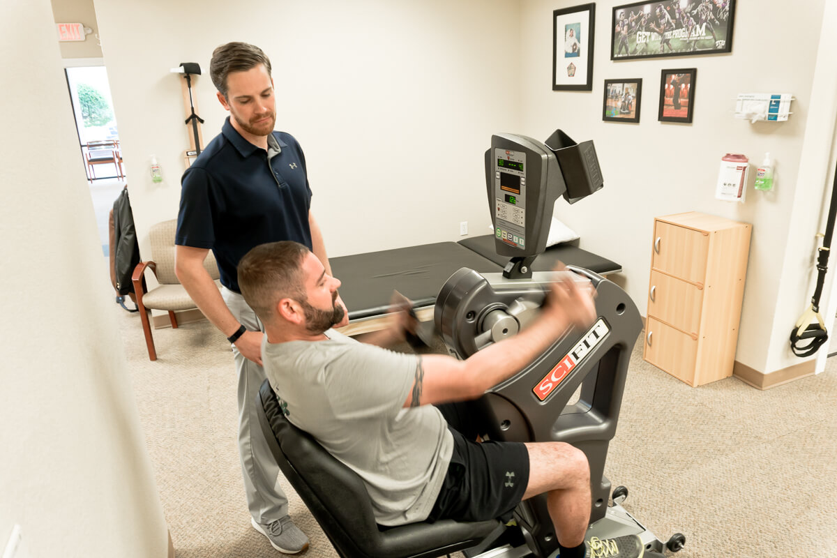 physical therapist working with patient on recumbent bike at fort worth physical therapy
