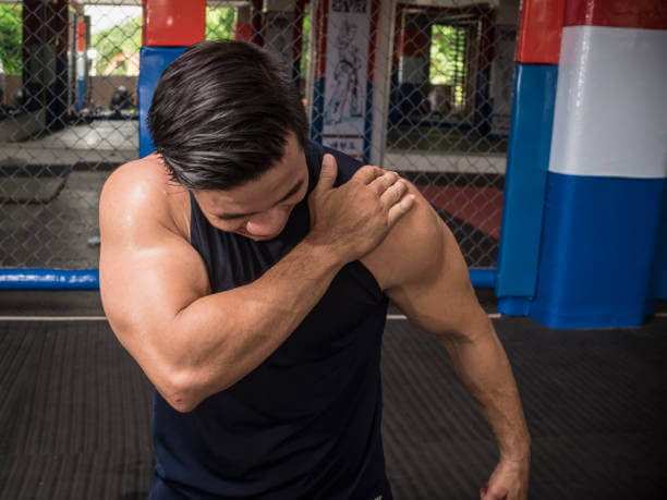 A fit man experiences rotator cuff tear, sprain or injury during a workout session at the gym.