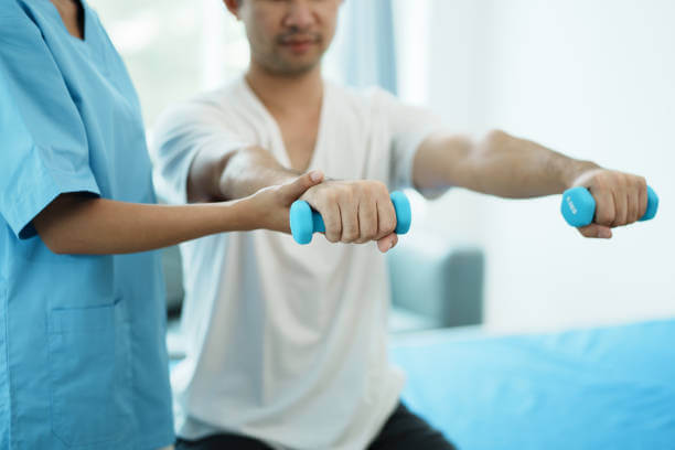 Physiotherapist treating rehabilitation arm pain patient doing physical therapy exercises.