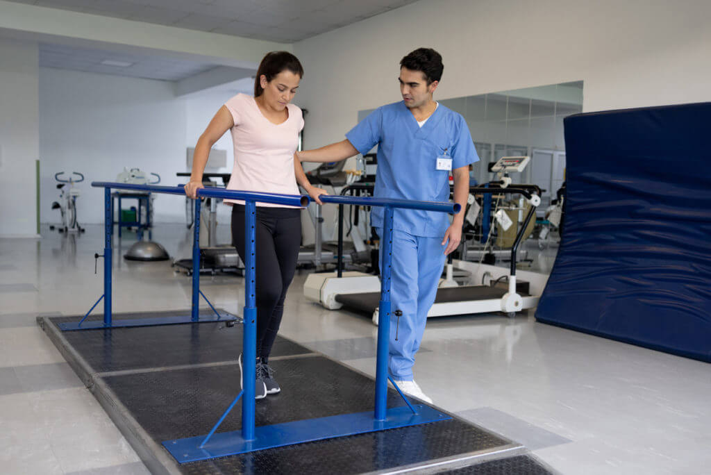 Woman in physical therapy walking on the parallel bars
