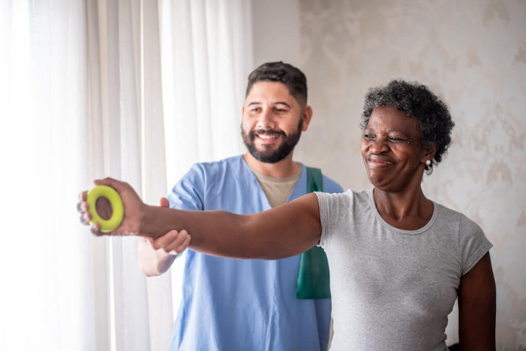 Mature woman doing physical therapy together with male nurse