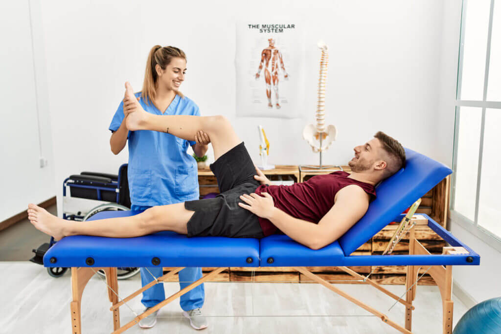 Young hispanic physical therapist woman make legs rehab treatment to man at the clinic
