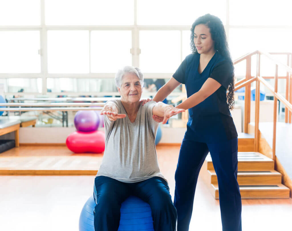 Senior woman sitting on fitness ball and exercising