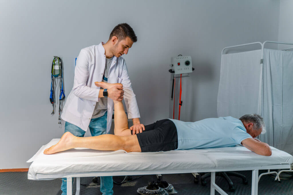 physical therapist stretching senior man's legs