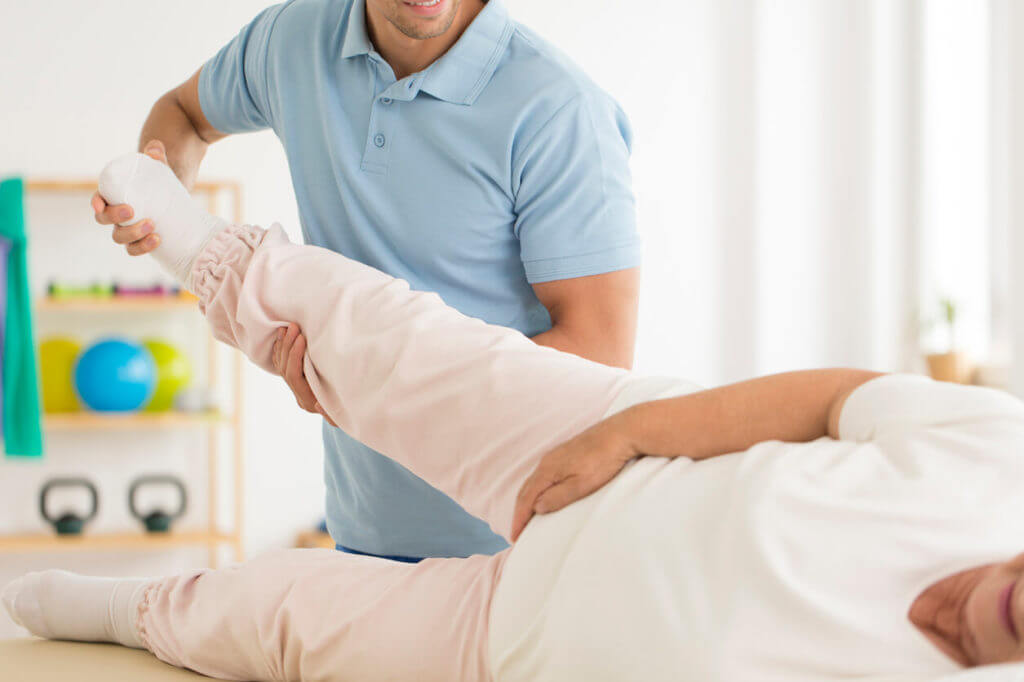 physical therapist rehabilitating hip joint after surgery