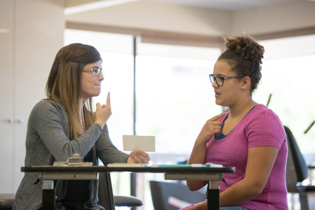 Female speech therapist helping a teenage patient inside of a clinic