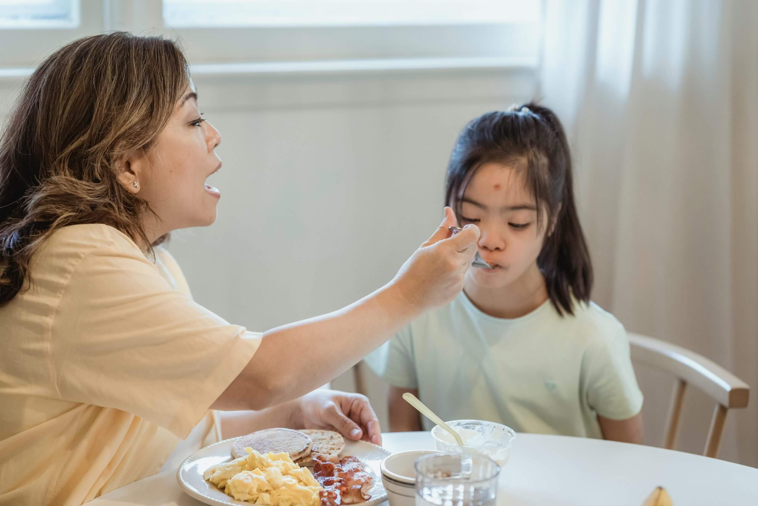 child with down syndrome receiving help with feeding therapy
