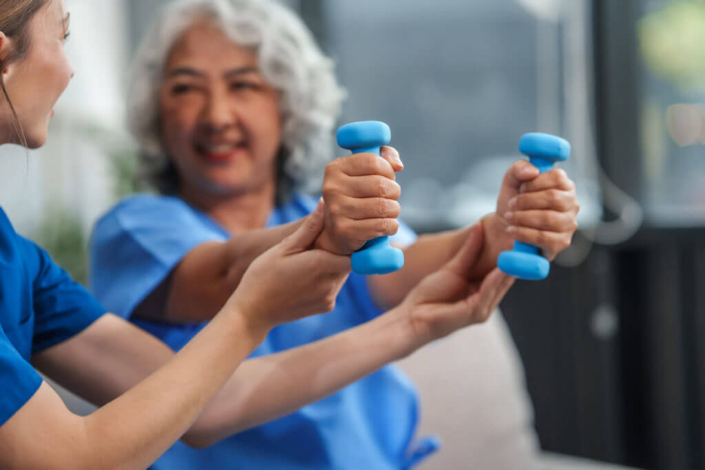 A young physical therapist is conducting a session with an elderly woman focusing on muscle pain and weakness.