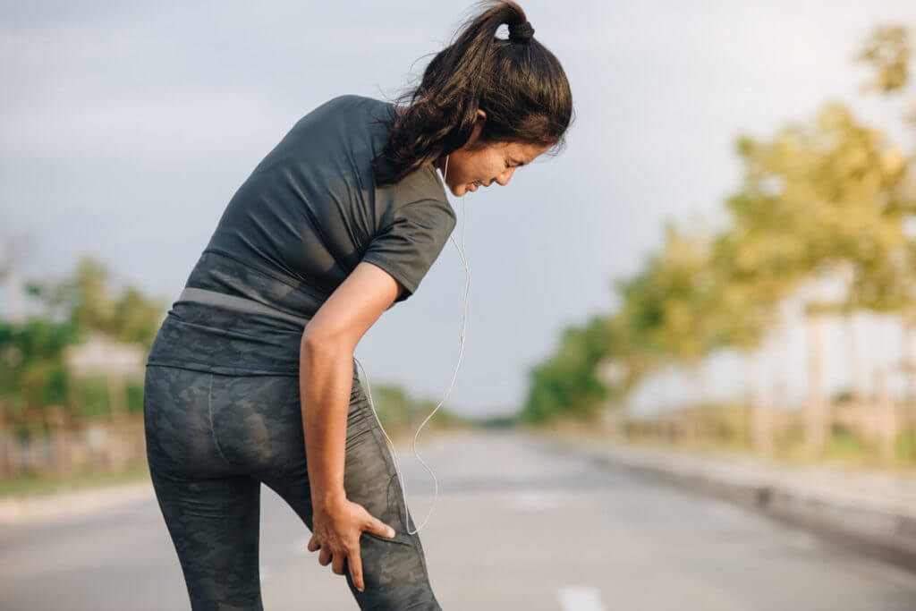 An image of a young woman experiencing a thigh muscle injury while running during exercise.