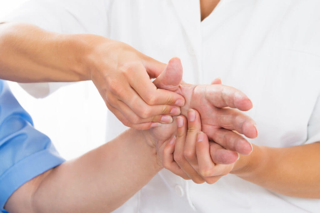 Specialist examining how well a patient is healing from a broken bone in the hand.