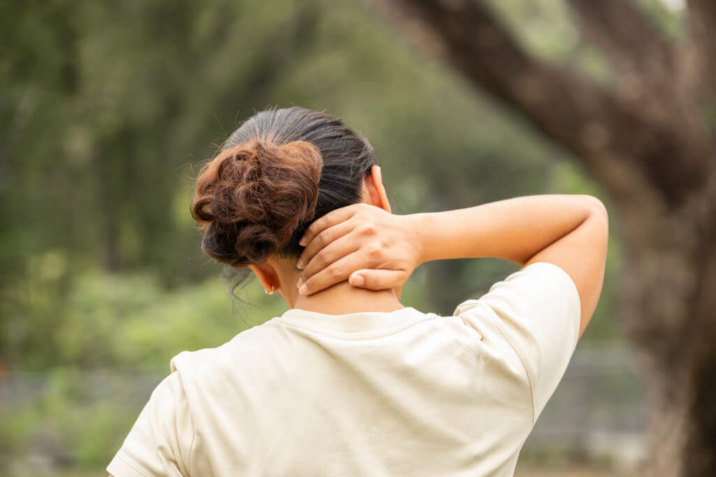 A woman is experiencing neck and shoulder pain as she massages the inflamed neck muscles.