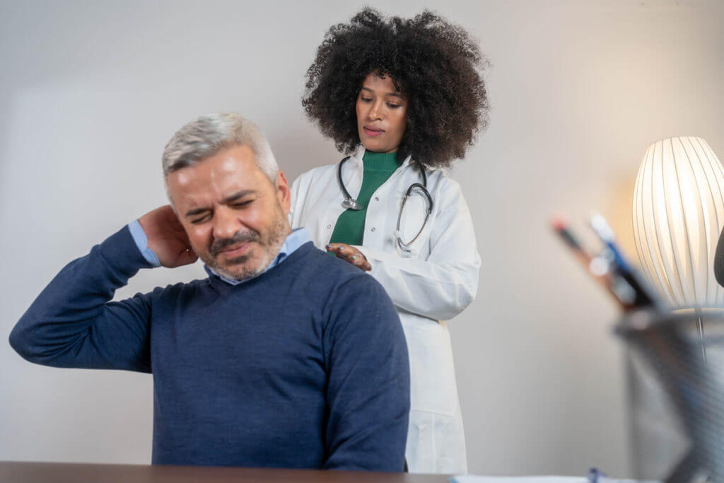 A senior man is undergoing a medical examination for neck pain at the office of a female physical therapist.