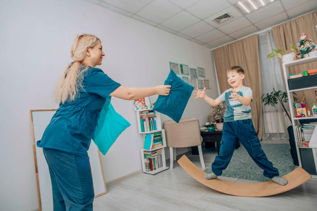 Pediatric physical therapist engaging child in balance and coordination activity during therapy session