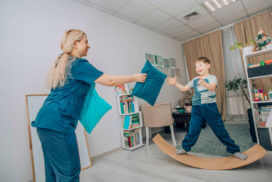 Pediatric physical therapist engaging child in balance and coordination activity during therapy session